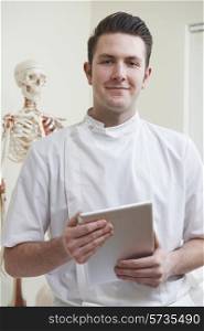 Portrait Of Osteopath In Consulting Room With Digital Tablet