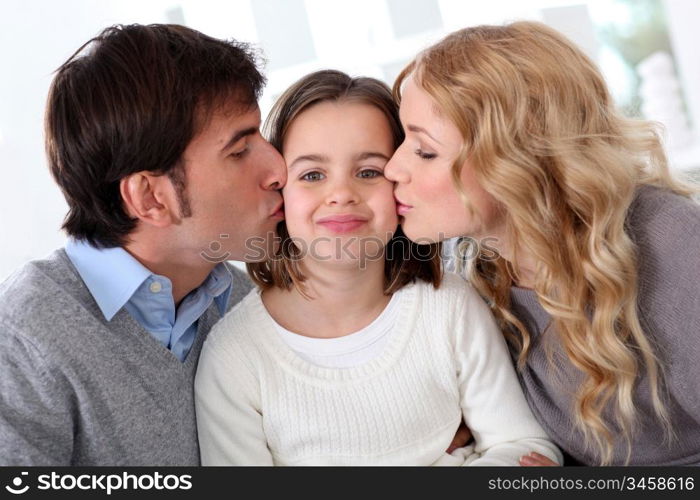 Portrait of parents kissing their daughter