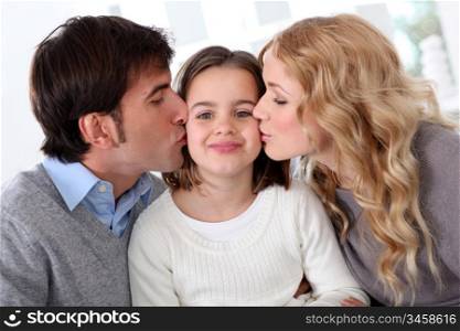 Portrait of parents kissing their daughter