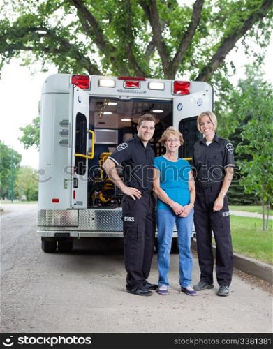 Portrait of patient with ambulance staff outside vehicle