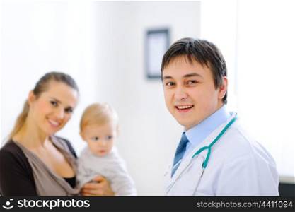 Portrait of pediatric doctor and smiling mother with lovely baby in background&#xA;