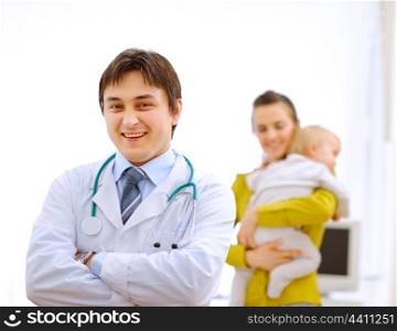 Portrait of pediatrician doctor and mother with baby in background&#xA;