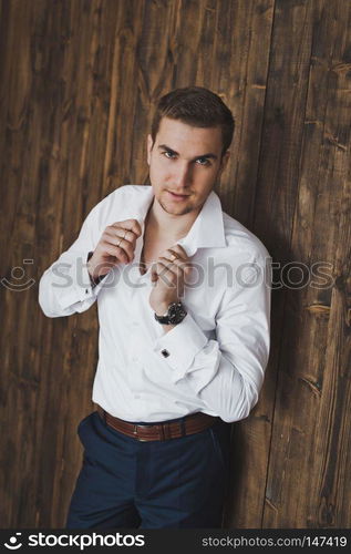 Portrait of pensive man on a background of a wooden wall.. Portrait of a man in a white shirt in the background of a wooden wall 6404.