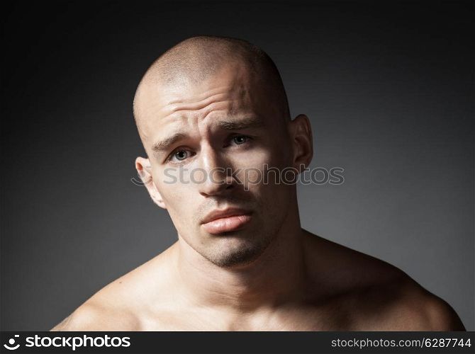 portrait of pitiful strong man isolated on gray background
