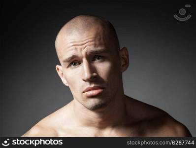 portrait of pitiful strong man isolated on gray background