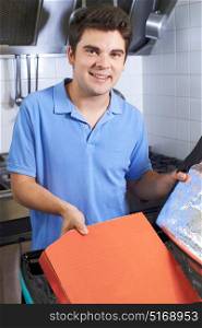Portrait Of Pizza Delivery Person Putting Food Into Insulated Bag In Restaurant Kitchen