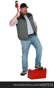portrait of plumber holding adjustable spanner with foot resting on toolcase