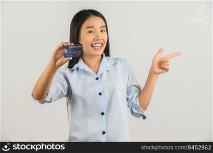Portrait of positive young asian woman showing credit card good mood salary and pointing finger at aside isolated on white background. Finance, currency, payment and people concept.