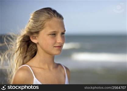Portrait of pre-teen girl on beach with ocean waves in background.
