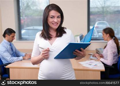 Portrait Of Pregnant Businesswoman Working In Office