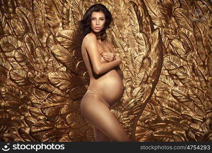 Portrait of pregnant lady over the golden wall