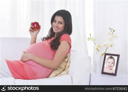 Portrait of pregnant woman holding an apple