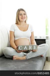 Portrait of pregnant woman holding letters making word Care