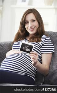 Portrait Of Pregnant Woman Holding Ultrasound Scan Of Baby