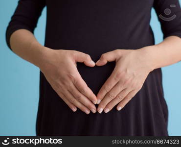 Portrait of pregnant woman over blue background. Portrait of happy pregnant woman with hands on belly isolated over blue background