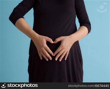 Portrait of pregnant woman over blue background. Portrait of happy pregnant woman with hands on belly isolated over blue background
