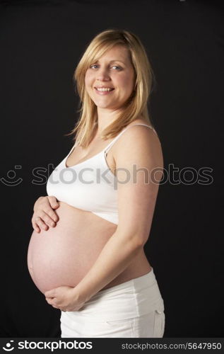 Portrait Of Pregnant Woman Wearing White On Black Background