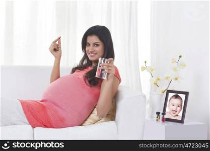 Portrait of pregnant woman with a pill and glass of water
