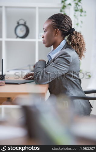 Portrait of pretty african female designer working with graphic tablet and computer at office