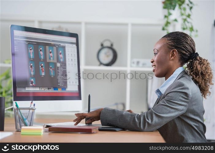 Portrait of pretty african female designer working with graphic tablet and computer at office