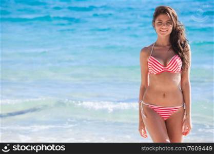 Portrait of pretty beautiful fashion woman in bikini posing in summer near the sea with gorgeous smile in happy mood on tropic island on vacation. Pretty woman in bikini near sea