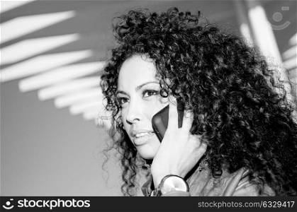 Portrait of pretty blak woman in urban background talking on phone