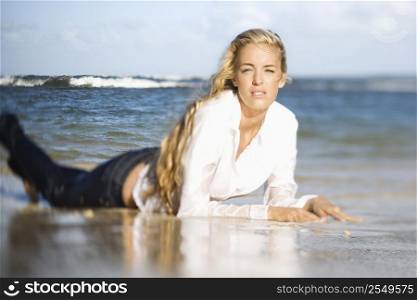Portrait of pretty blond Caucasian woman lying on stomach on Maui, Hawaii beach.