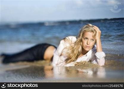 Portrait of pretty blond Caucasian woman lying on stomach on Maui, Hawaii beach.