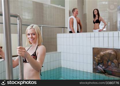 Portrait of pretty blond girl in the pool with people in background