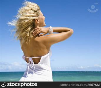 Portrait of pretty blond woman smiling standing on Maui, Hawaii beach looking out towards ocean.