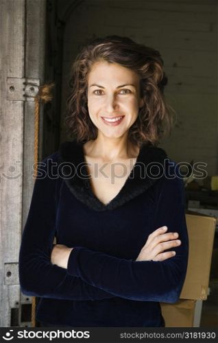 Portrait of pretty Caucasian woman standing with arms crossed smiling.
