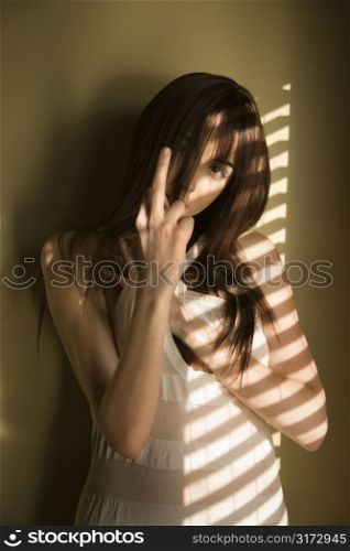 Portrait of pretty Caucasian young woman standing against wall giving middle finger.