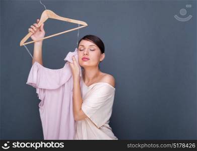 Portrait of pretty fashionable woman trying new clothes. Fashion poster shot indoors at studio against grey background.