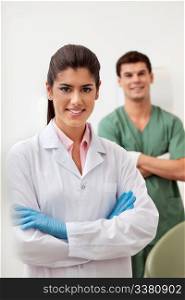 Portrait of pretty female dentist arms crossed with colleague standing behind