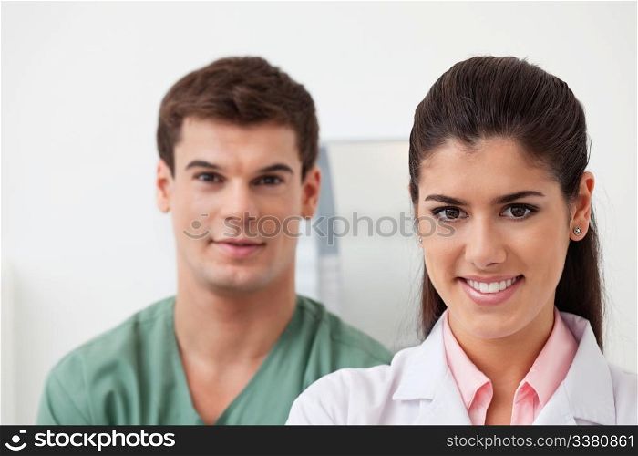 Portrait of pretty female doctor smiling with colleague standing behind