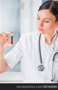Portrait of pretty female laboratory assistant analyzing a blood sample at hospital