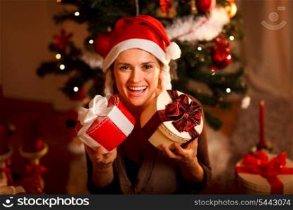 Portrait of pretty girl near Christmas tree holding present boxes &#xA;