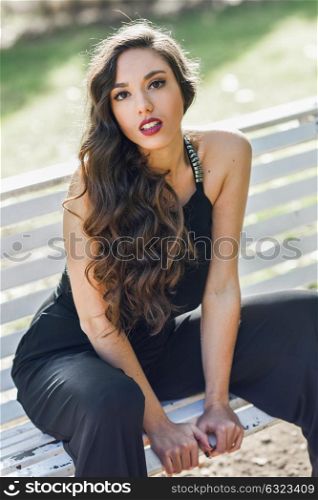 Portrait of pretty girl with long hair wearing black clothes in a park