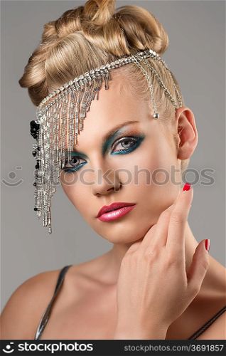 portrait of pretty girl with the elegant hair style and indian decoration on the head, she looks in to the lens with one hand near the face