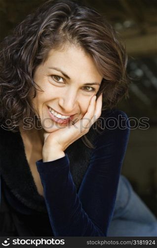 Portrait of pretty mid adult Caucasian woman smiling with head on hand making eye contact.