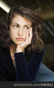 Portrait of pretty mid adult Caucasian woman with head on hand looking out to side.