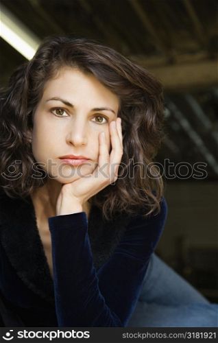 Portrait of pretty mid adult Caucasian woman with head on hand making eye contact.