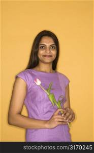 Portrait of pretty mid adult Indian woman holding tulip flower.