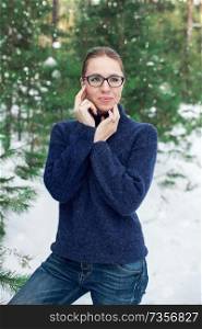 Portrait of pretty woman in a woolen blue sweater in the winter forest. Winter holidays concept or forest walking.. Portrait of pretty woman in a woolen blue sweater in the winter forest