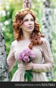 Portrait of pretty woman in the park standing near birch tree and dreamy looking in side, gentle bride with flower enjoying spring nature
