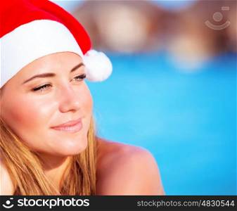 Portrait of pretty woman wearing red Santa hat, Christmastime holidays on the beach on exotic island, luxury winter time vacation concept