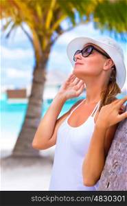 Portrait of pretty woman wearing white hat and sunglasses enjoying bright sun light, happy summer holidays, tropical resort on Maldives