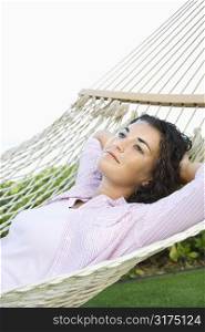 Portrait of pretty young adult Caucasian brunette female lying in hammock relaxing.