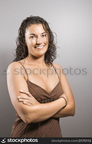 Portrait of pretty young adult Caucasian brunette female with arms crossed smiling and looking at viewer.