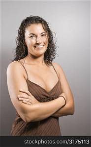 Portrait of pretty young adult Caucasian brunette female with arms crossed smiling and looking at viewer.